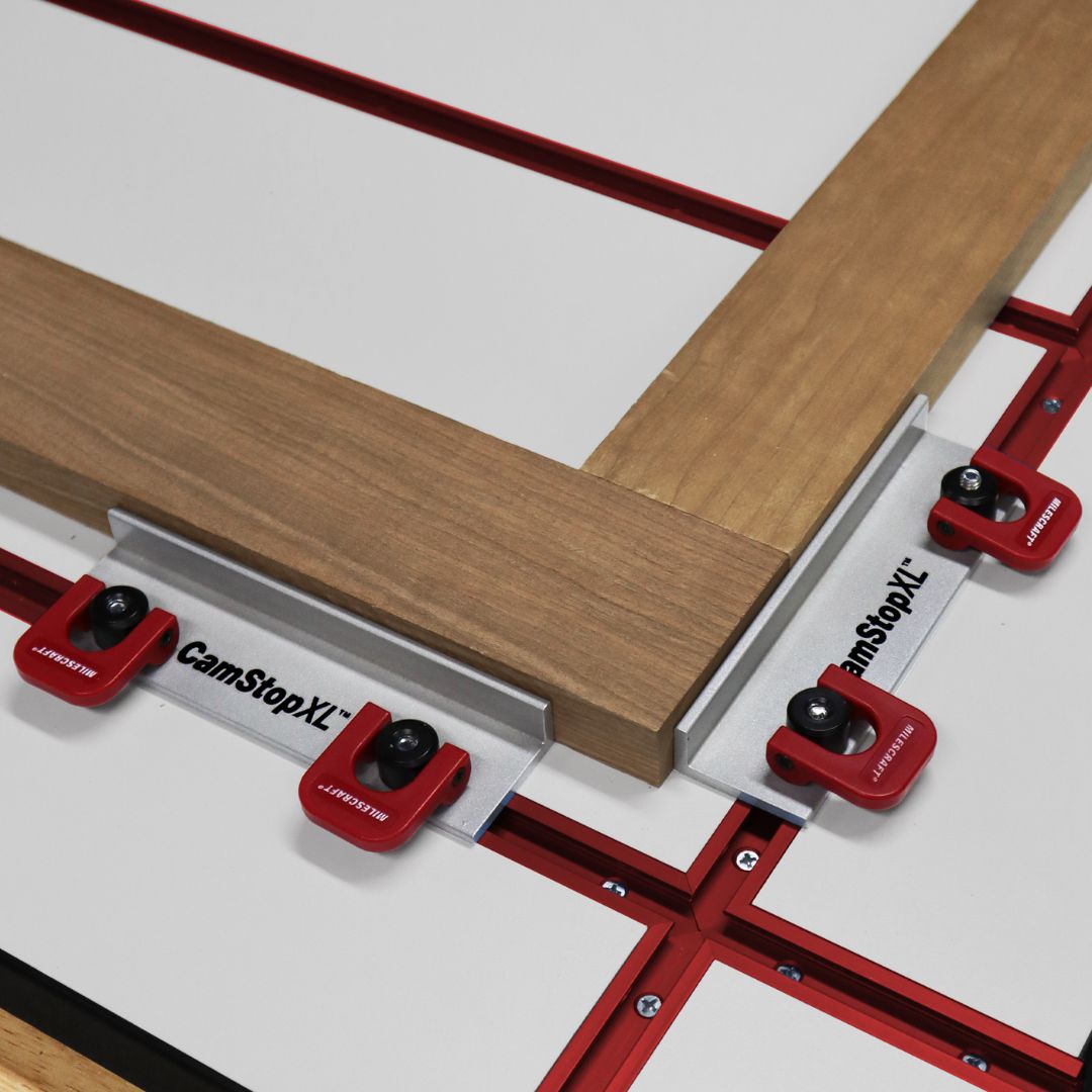 Woodworking setup with 'CamStop XL' clamps holding a piece of wood in place.